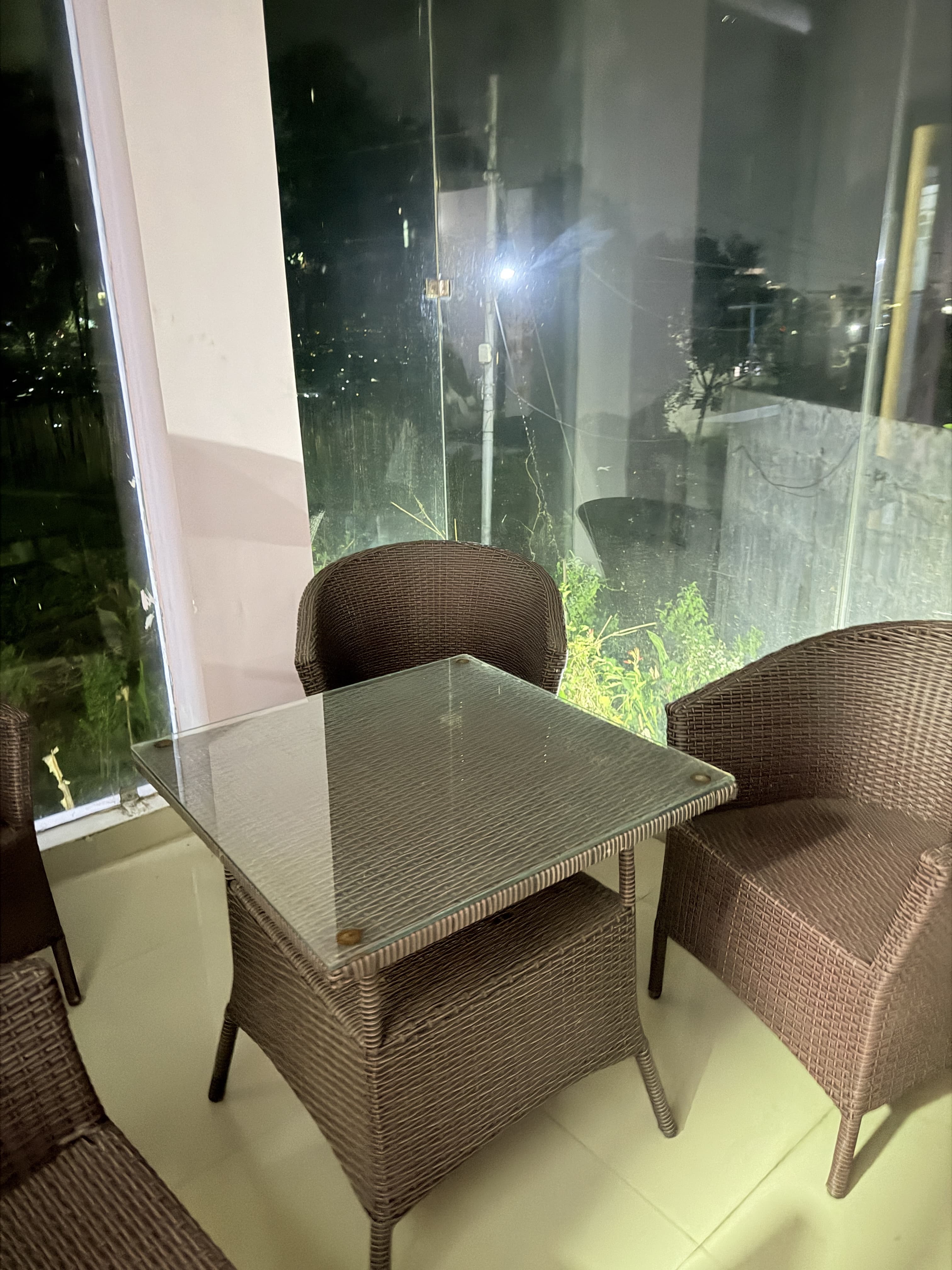 Balcony terrace with wicker armchairs and glass coffee table overlooking lush hillside