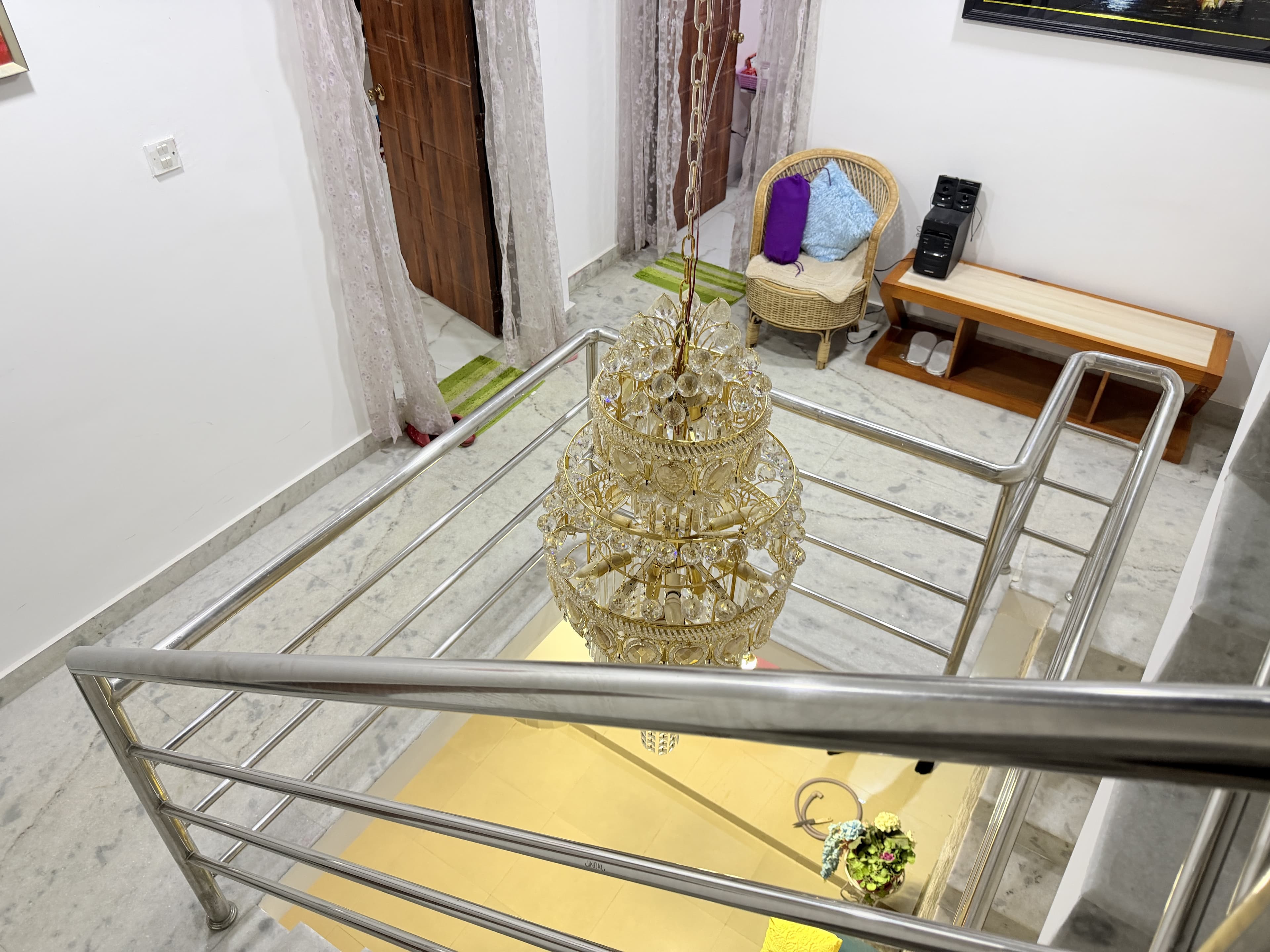 Helical cascading crystal LED chandelier through multi-story staircase with wicker armchair