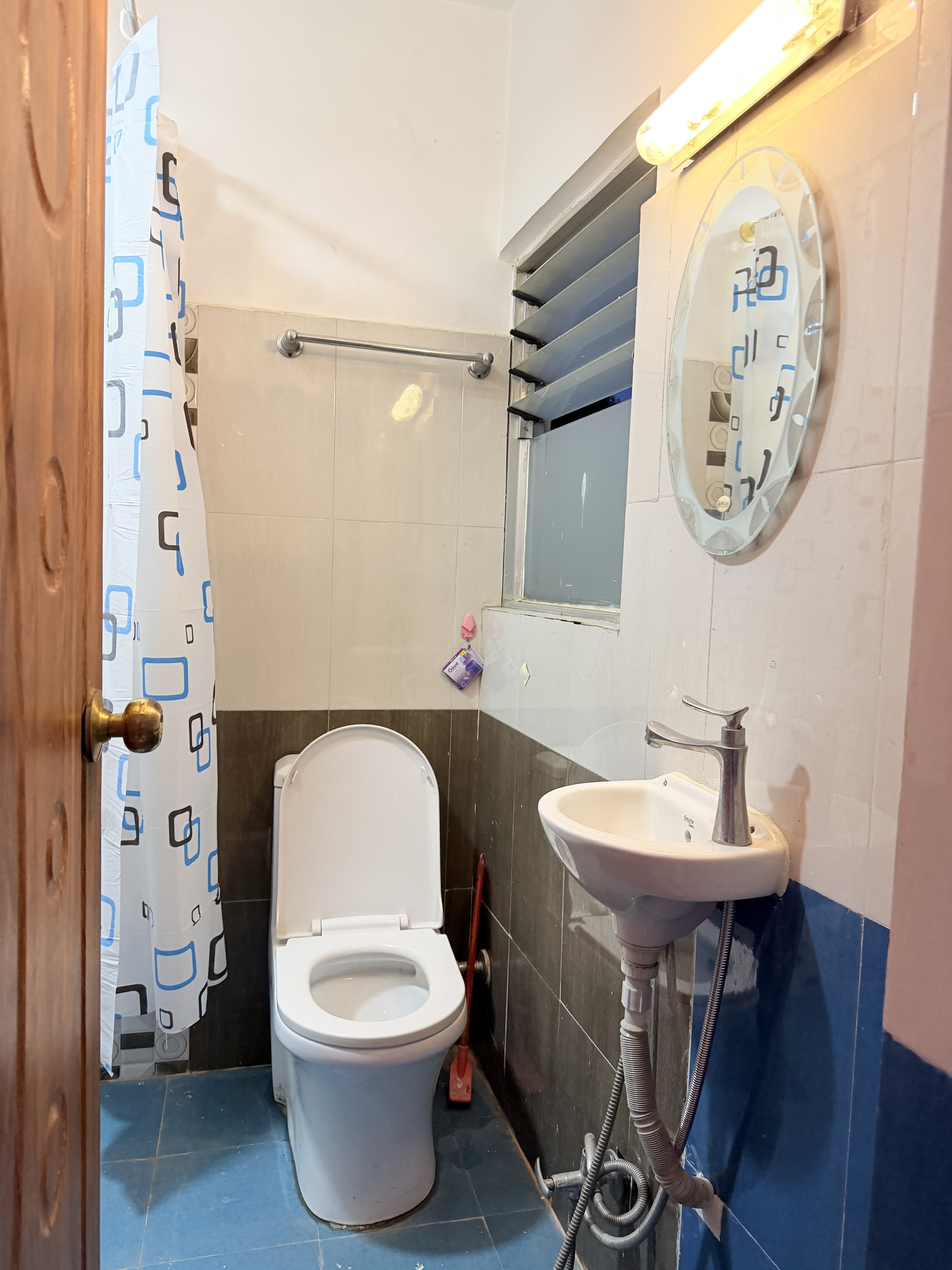 Modern private washroom with ceramic basin, chrome faucet, illuminated oval mirror, and tile finishes
