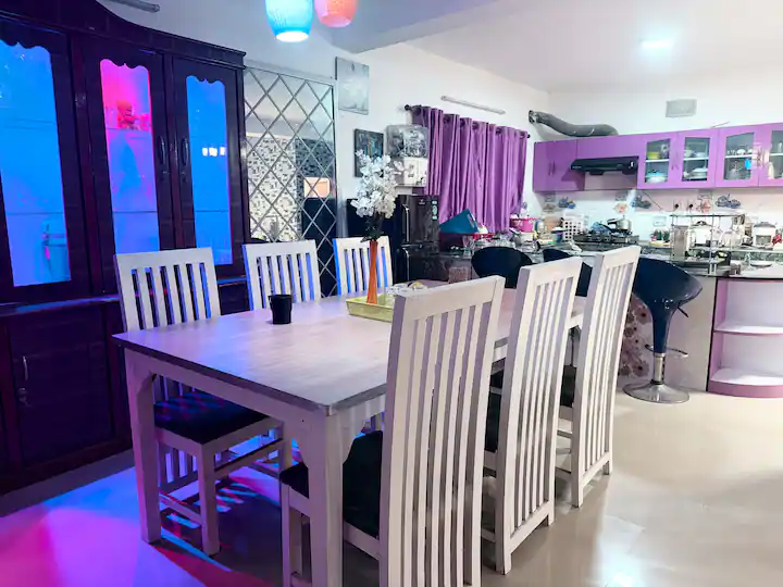 Dining area with white wooden table and kitchen with bar seating