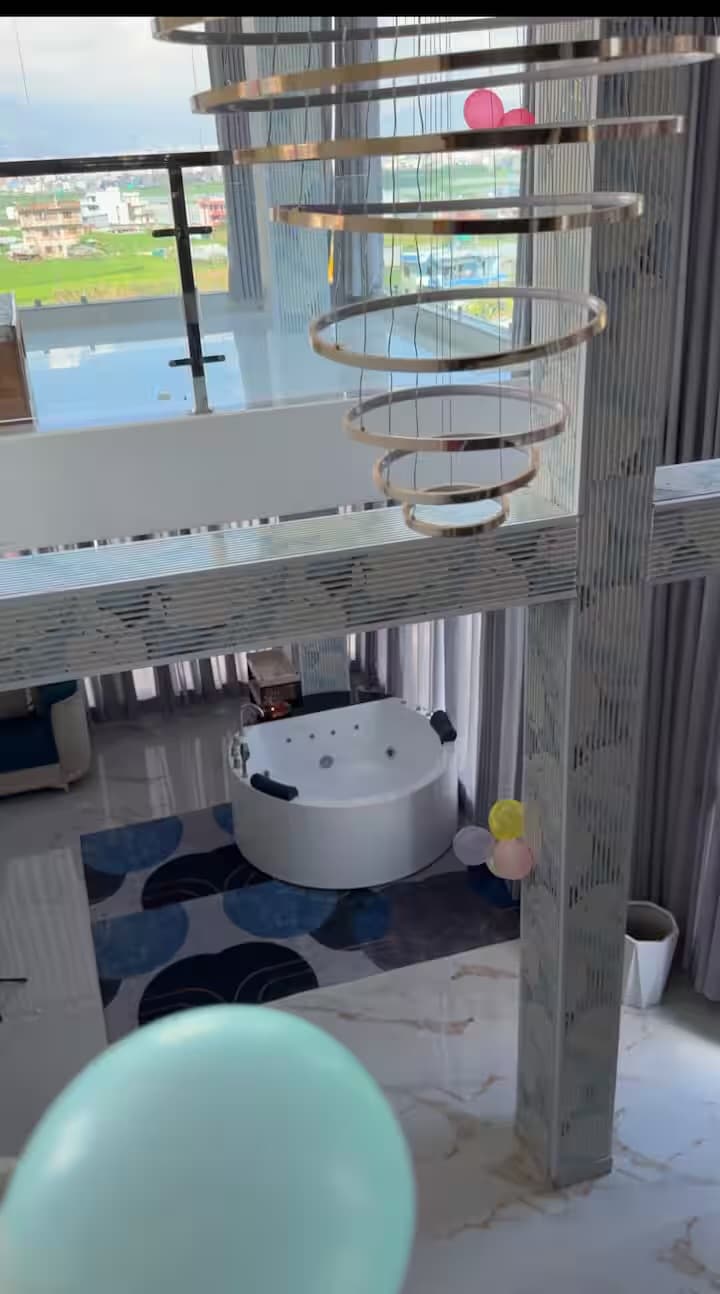 Double-height interior with cascading chandelier, jacuzzi, and valley panorama through floor-to-ceiling windows